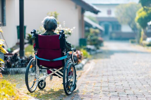 An elderly woman in a wheelchair. The woman's back is to the camera.